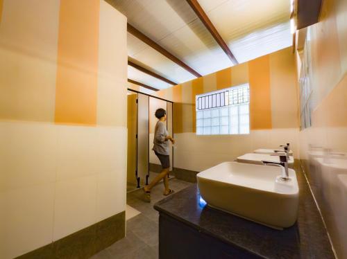 a person walking into a bathroom with a sink at Maison Monty in Pondicherry