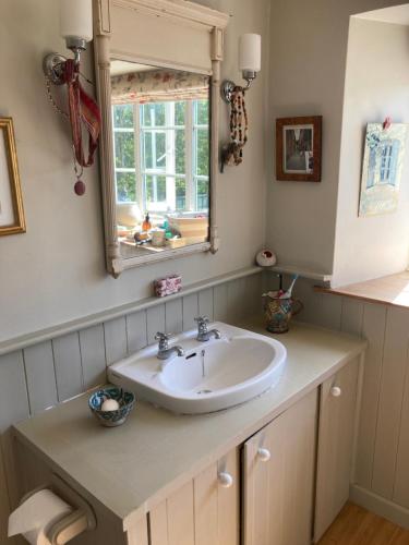a bathroom with a sink and a mirror at Brook Farm Cottage in Brackley
