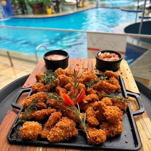 a tray of food on a table next to a pool at Village Park Hotel in Pires Ferreira