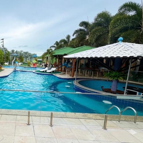 a large swimming pool with chairs and an umbrella at Village Park Hotel in Pires Ferreira