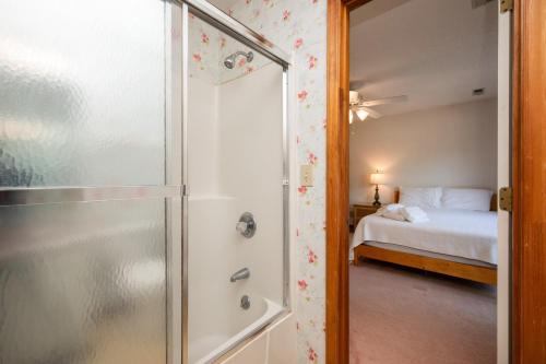 a bathroom with a shower and a bedroom with a bed at The Rectory by Oak Island Accommodations in Oak Island