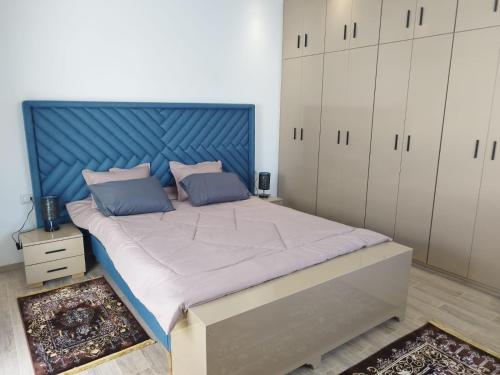 ein großes Bett mit blauem Kopfteil in einem Schlafzimmer in der Unterkunft Djerba Aldo Piscine in Houmt Souk