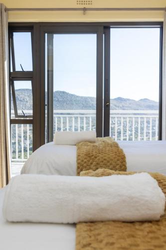 a bedroom with two beds and a large window at Stunning Ocean & Mountain View Apartment in Glencairn