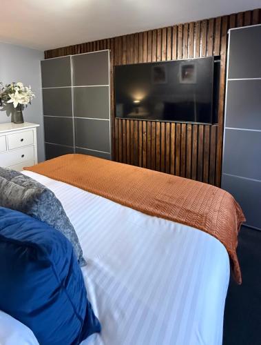 a bedroom with a bed with a tv on the wall at George Cottage, Alcester in Alcester