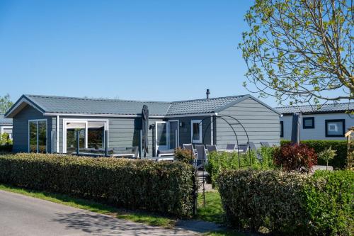 a blue house with bushes in front of it at Luxe Chalet Jara JS17 Oostkapelle in Oostkapelle