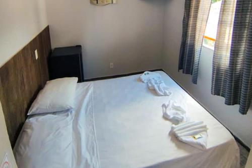 a bed with white sheets and towels on it at VELINN Pousada Entre Praias Itaguá in Ubatuba