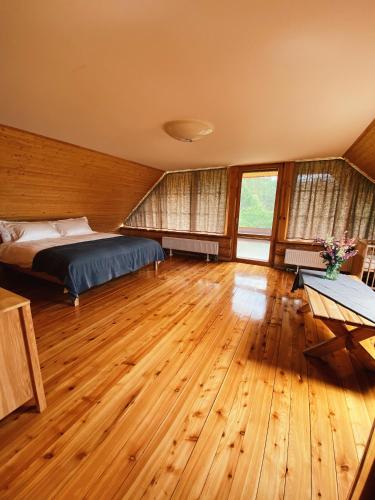 a bedroom with a bed and wooden floors and windows at Silmaļi Tērvetē in Tērvete
