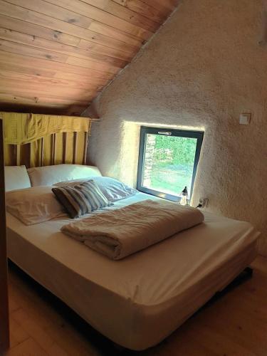 a large bed in a room with a window at Charmante longère forestière proche Lac de Guerlédan in Sainte-Brigitte