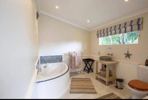 a bathroom with a tub and a toilet and a sink at Waterford Manor in Henburg Park