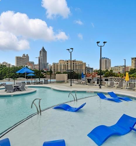 a pool with blue chairs and a city in the background at Midtown King Bed Suite - Pool - Gym - Parking - Tennis Court in Atlanta