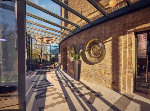 un patio con una pared de ladrillo y un techo en Wasserturm Hotel Cologne, Curio Collection by Hilton, en Colonia