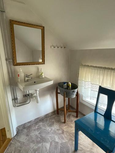 a bathroom with a sink and a mirror and a chair at Brunnsta Gård in Bålsta
