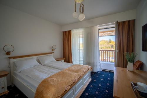 a bedroom with a large bed and a balcony at Pensiunea Bila in Naipu