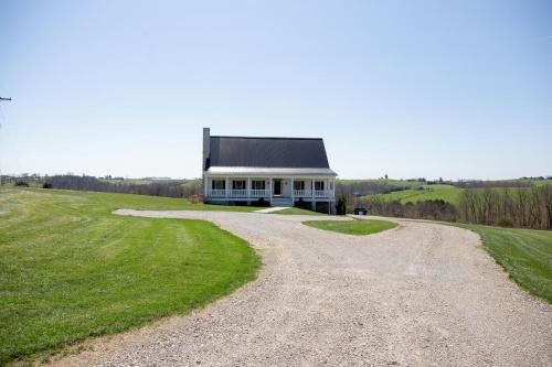 a gravel road leading to a white house on a hill at The Gathering Premier stay for Large Groups in Millersburg
