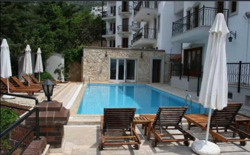 a swimming pool with chairs and umbrellas next to a building at Grand süit in Kalkan