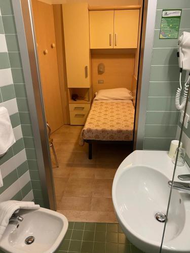 un bagno con lavandino e una camera da letto con letto di Hotel Lazzarini a Bellaria-Igea Marina