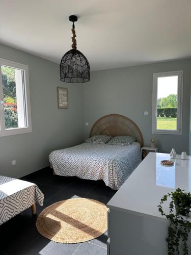 a bedroom with a bed and a table and windows at L'échappée Belle Maison entre Pins et Océan in Bias