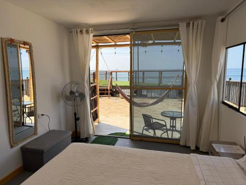 a bedroom with a bed and a view of a balcony at Surf & Sand Lobitos in Lobitos