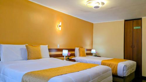 two beds in a hotel room with yellow walls at Hotel San Lázaro Arequipa - Cochera - Hotel en Arequipa in Arequipa