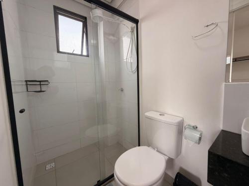 a bathroom with a toilet and a glass shower at Studio Smart Ponte da Amizade in Foz do Iguaçu