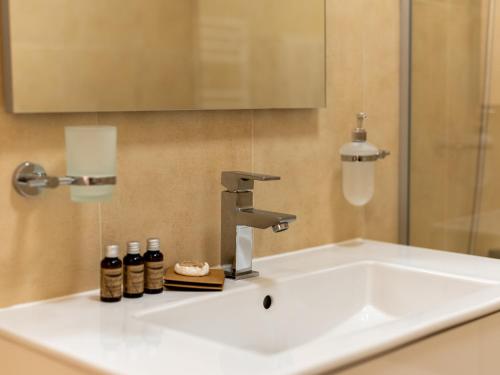 a bathroom sink with a faucet and bottles on it at Pensiunea Bila in Naipu