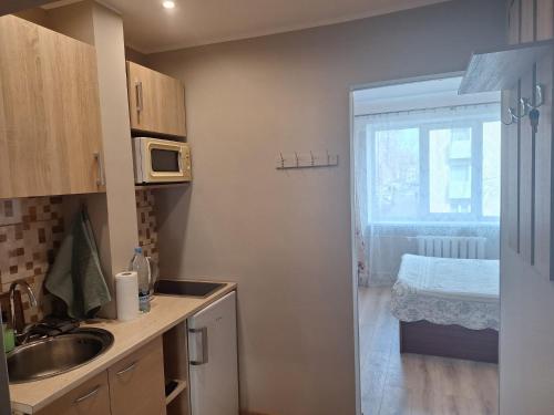 a kitchen with a sink and a window with a bed at Тоmiк Liepaja in Liepāja