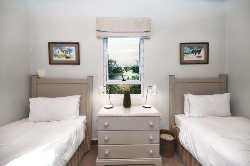 a bedroom with two beds and a window at Walk Waterfront CliffPath Fireplace Secure-Parking in Hermanus