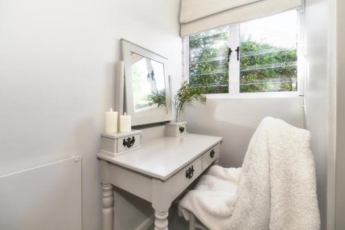 a white dressing table with a mirror and a window at Walk Waterfront CliffPath Fireplace Secure-Parking in Hermanus