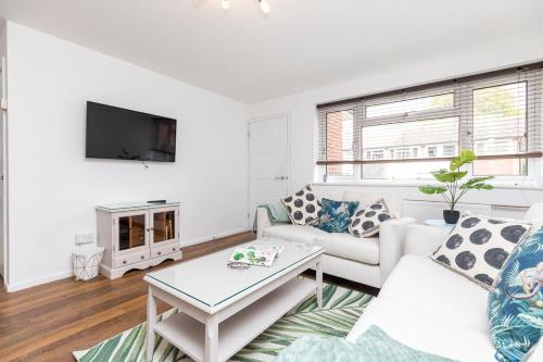 a white living room with a couch and a tv at Rivermead - Gorgeous 3 Bed Maisonette with Patio in Horsham