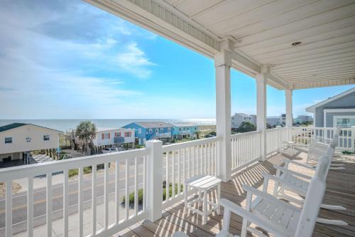 a porch with two white chairs and a view of the ocean at Wait N Sea by Oak Island Accommodations in Oak Island