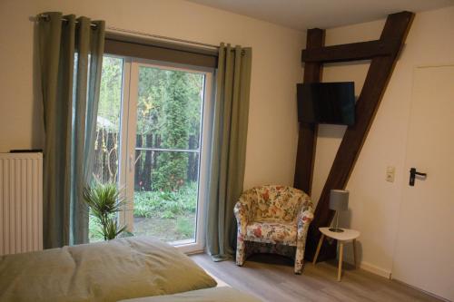 a bedroom with a bed and a chair and a window at Dahlmanns Pension am Park in Oranienbaum-Wörlitz