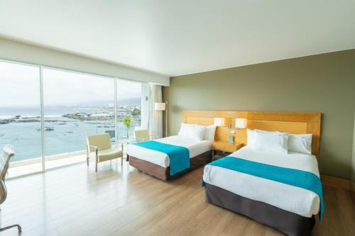 a hotel room with two beds and a large window at Terrado Suites Antofagasta in Antofagasta