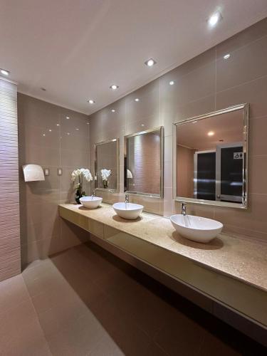 two sinks in a bathroom with two mirrors at Hotel Capelli Talca in Talca