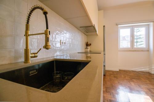 a large kitchen with a sink and a window at Casa do Largo Ericeira in Ericeira