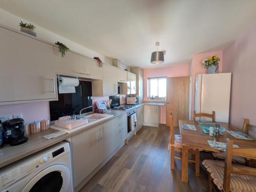 a kitchen with white cabinets and a table and a dining room at Beachwood in Skegness