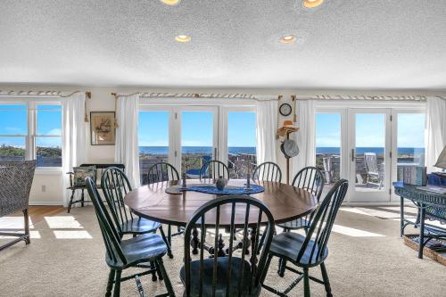 a dining room with a table and chairs and windows at Jonahs Whale by Oak Island Accommodations in Caswell Beach