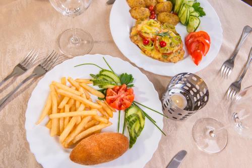 a table with two plates of food and french fries at Hotel Zemaites in Vilnius