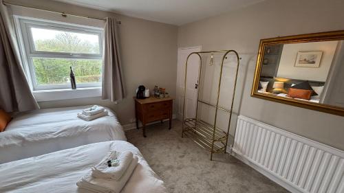 a bedroom with two beds and a mirror and a window at Jack & Jill Inn Pub in Hassocks