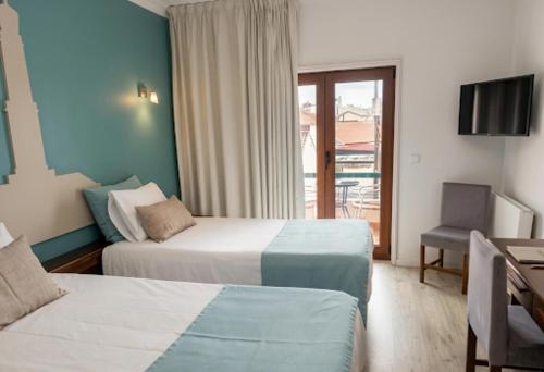 a hotel room with two beds and a desk at Hotel Areias Claras in Viana do Castelo