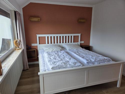 a white bed in a room with a window at Lüdde Stuv am Meer in Husum