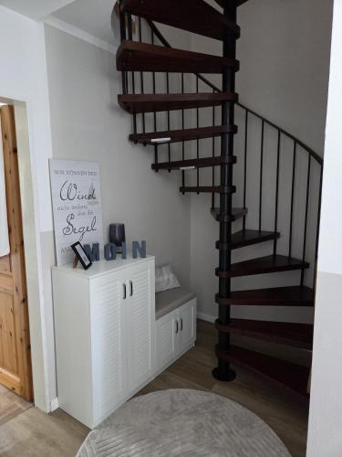 a spiral staircase in a living room with a shelf at Lüdde Stuv am Meer in Husum