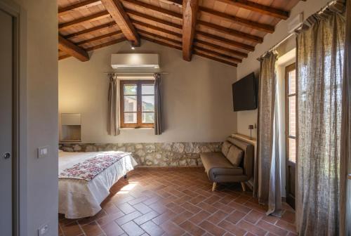 a bedroom with a bed and a chair and a window at Agriturismo La Vecchia Quercia in Montemerano