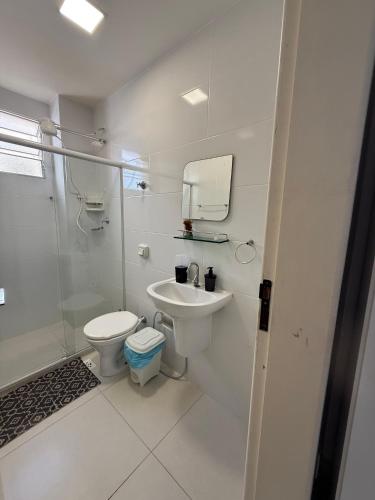 a white bathroom with a toilet and a sink at Quitinete Centro de Guarapari. in Guarapari