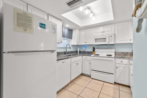 a kitchen with white appliances and white cabinets at Sand Between Stays in Orange Beach