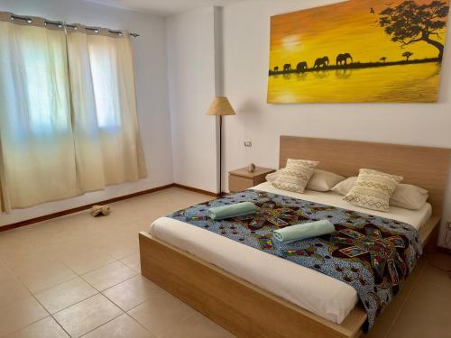 a bedroom with a bed with a painting on the wall at Kasa n'areia, Praia Estoril in Sal Rei