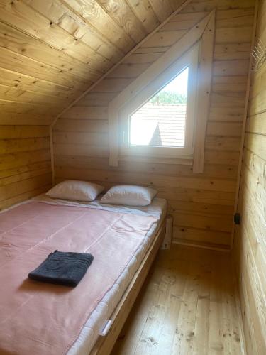 a bed in a wooden cabin with a window at Агрооселя Ростоки in Zhdanivka