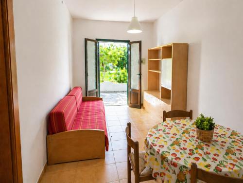 a living room with a table and a red couch at Cala Dei Saraceni in Peschici