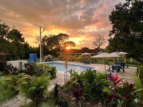 a pool with tables and umbrellas at sunset at Finca Hotel La Herencia Cafetera in Montenegro