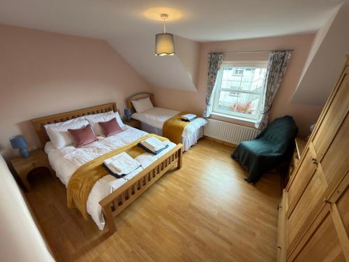 a bedroom with a large bed and a green chair at 10 Mill Square in Portstewart