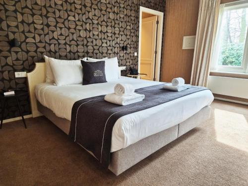 a bedroom with a large bed with towels on it at Kasteel De Vanenburg in Putten